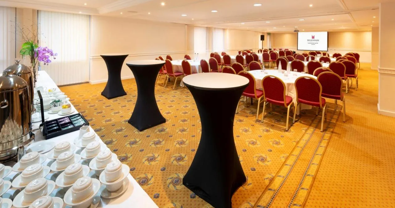 a conference room with tables and chairs and a screen at Millennium Hotel and Conference Centre Gloucester London in London